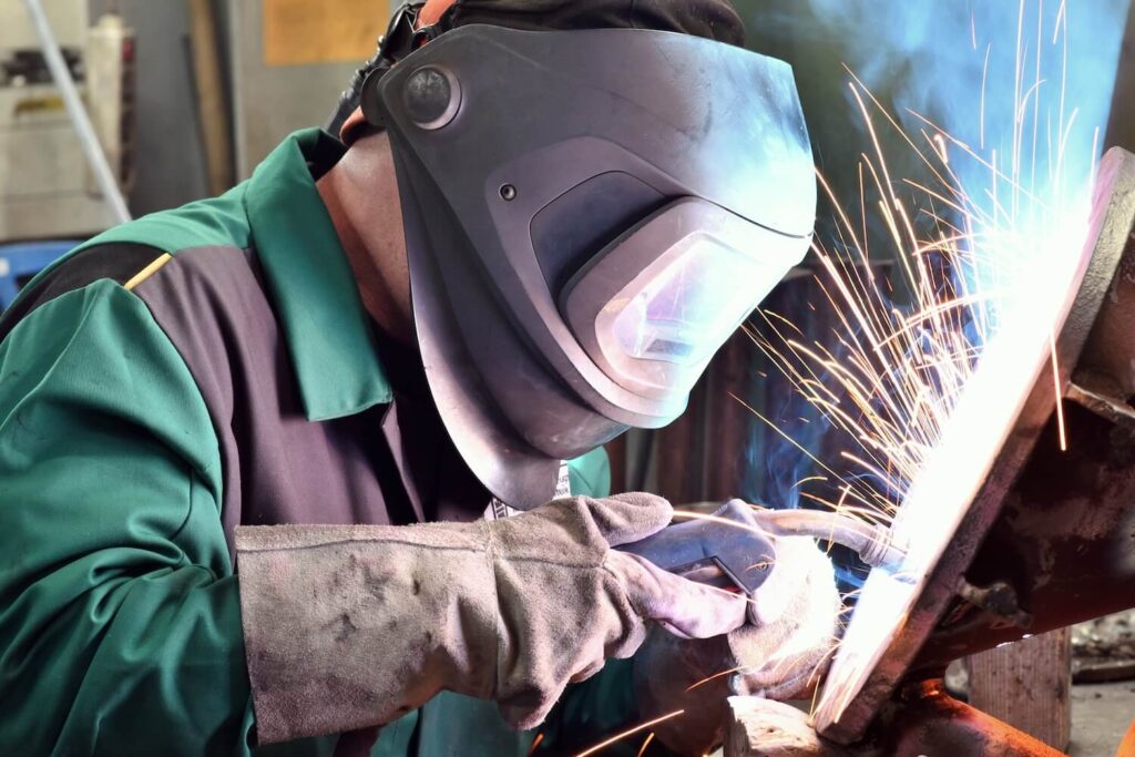 Welder in protective clothing at the workplace in an industrial company in steel construction